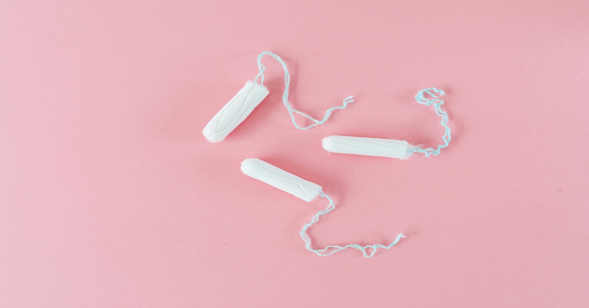 Three tampons lying on a pink surface.