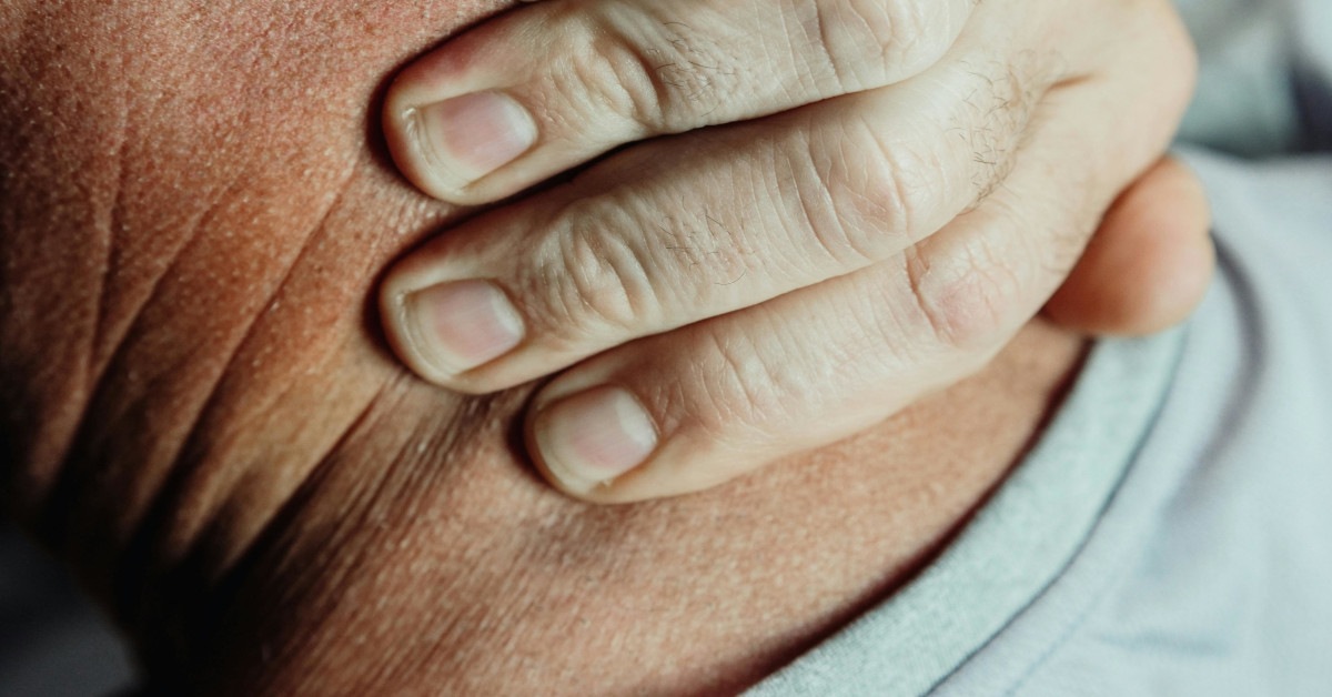 A man putting his hand on his neck indicating neck pain.