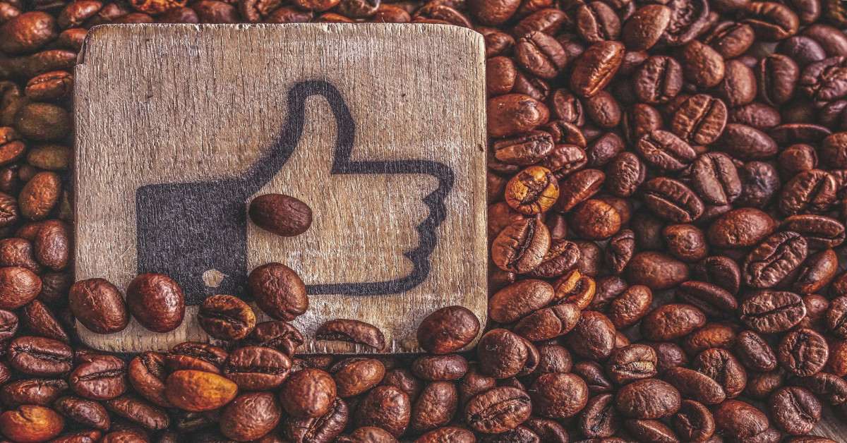 A thumbs up emoji lying in the middle of coffee beans.