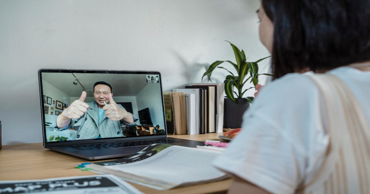 A counselor giving a thumbs up to his client through the laptop screen.