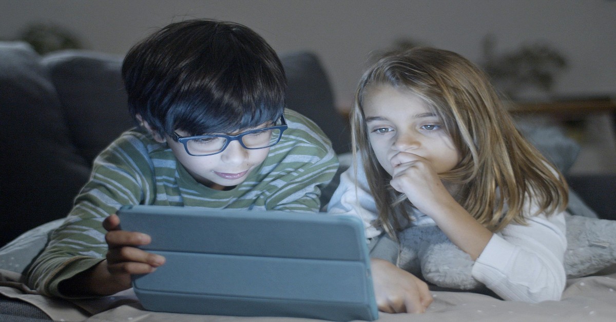 Two children looking at a tablet together.