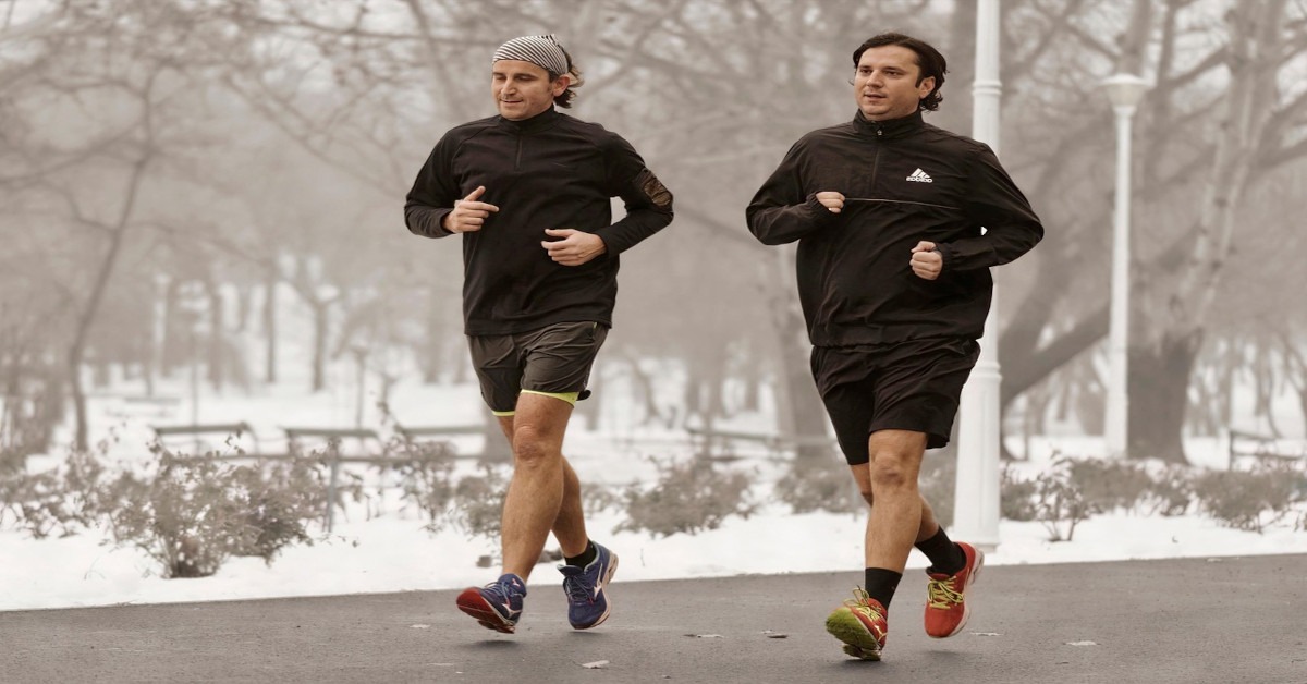 Two guys running together on the street.