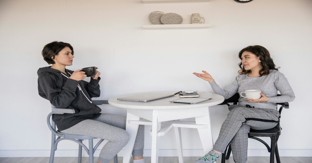 Two women talking to each other over a cup of coffee.