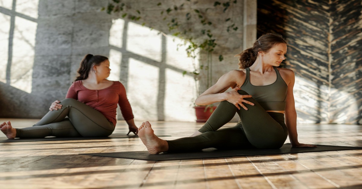 Two women are stretching together on the floor.