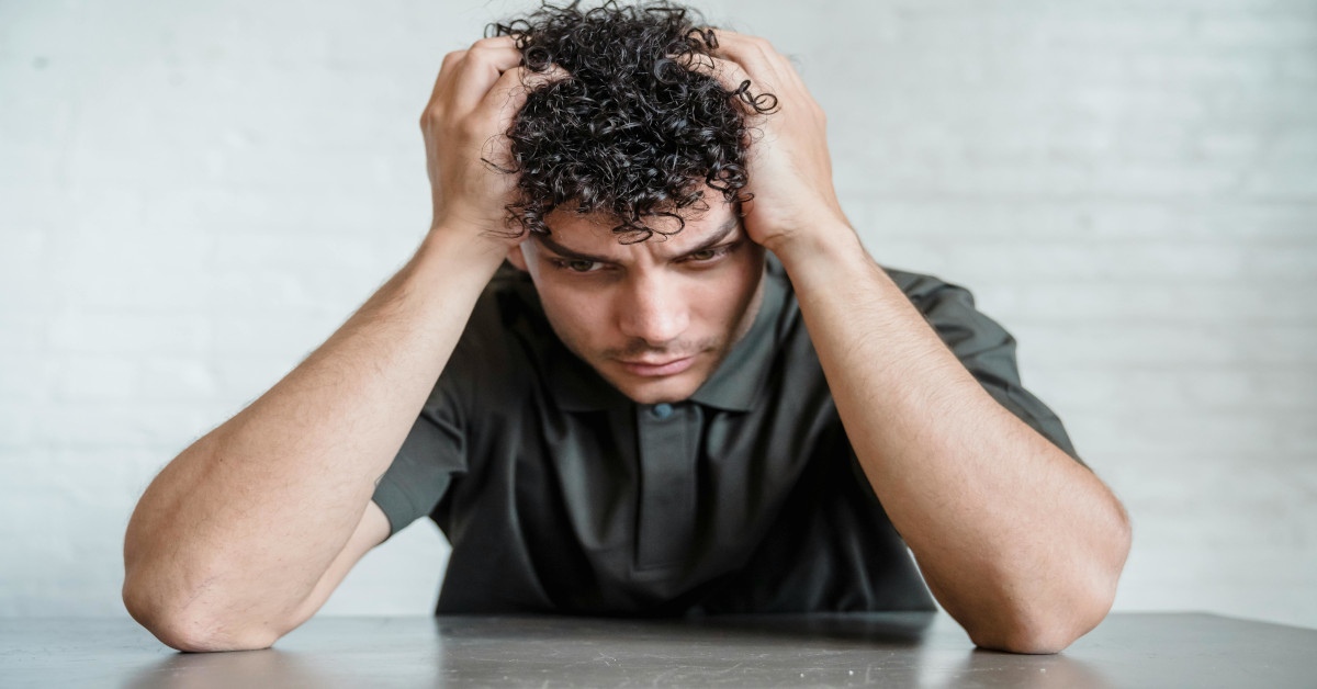An upset man holding his head while thinking.