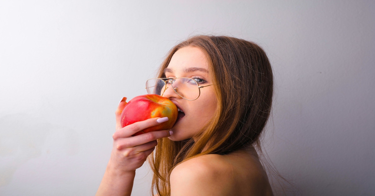 Side view of a woman biting in an apple.