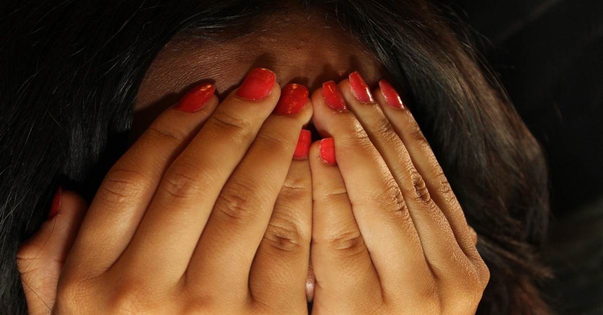 A woman covering her face in shame.