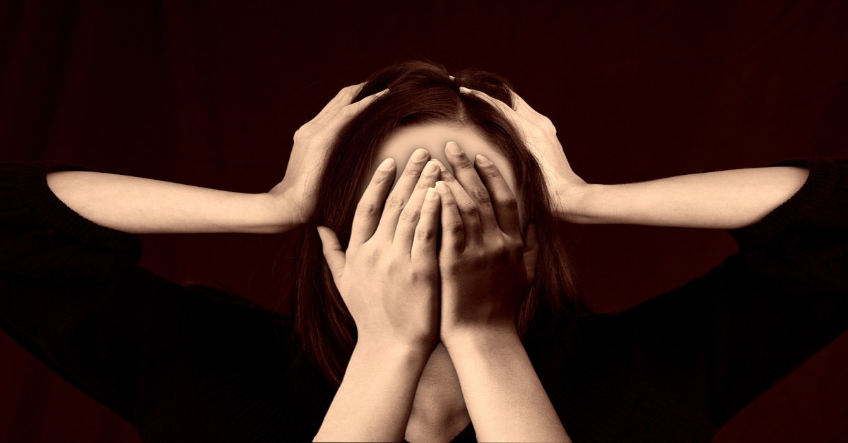 A woman holding her head while two other hands are covering her eyes.