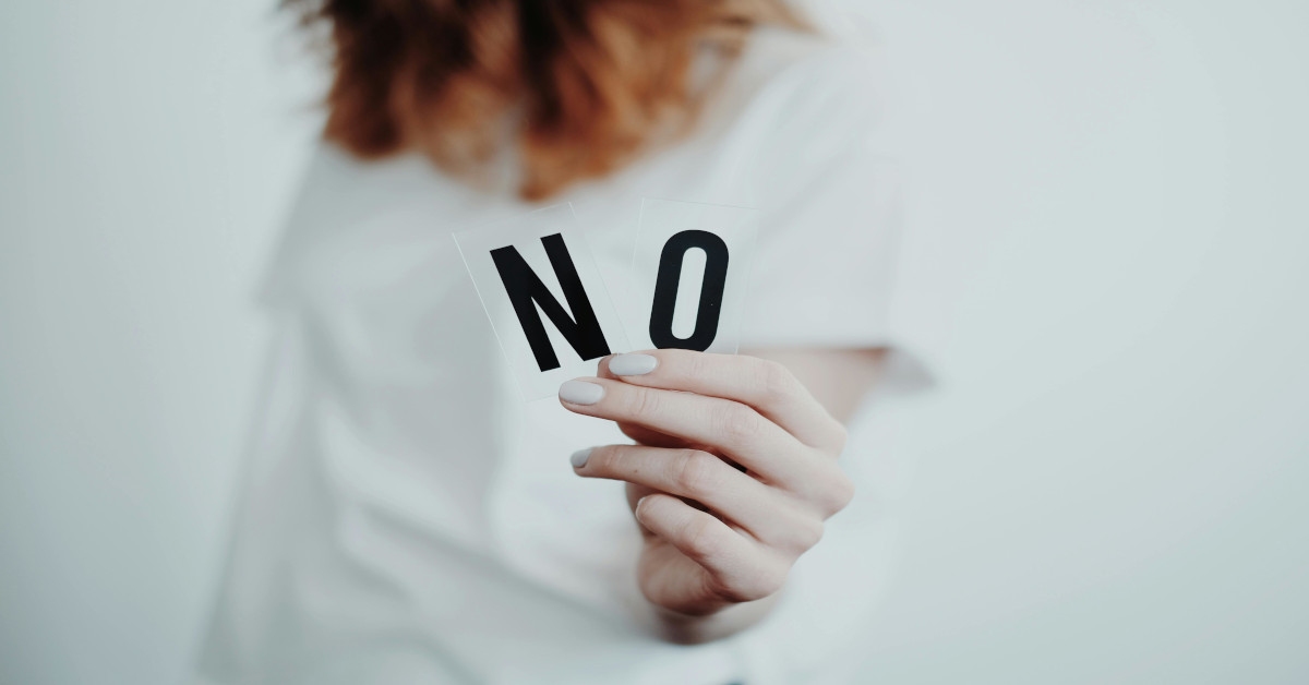 Woman holding the letters "N" and "O" in her hands, forming the word "no".