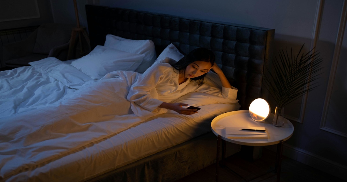 A woman using her phone in bed because she can't sleep.