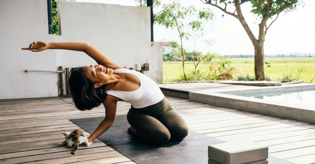 A woman doing a side stretch while sitting on her knees.