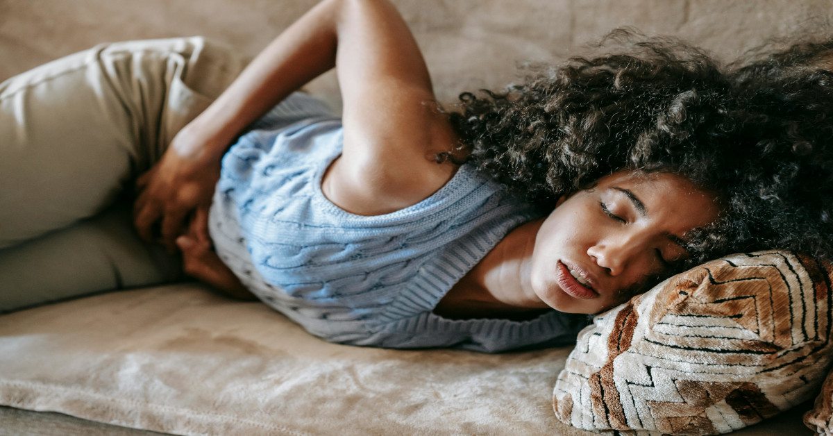 A woman suffering from stomach pain in bed.