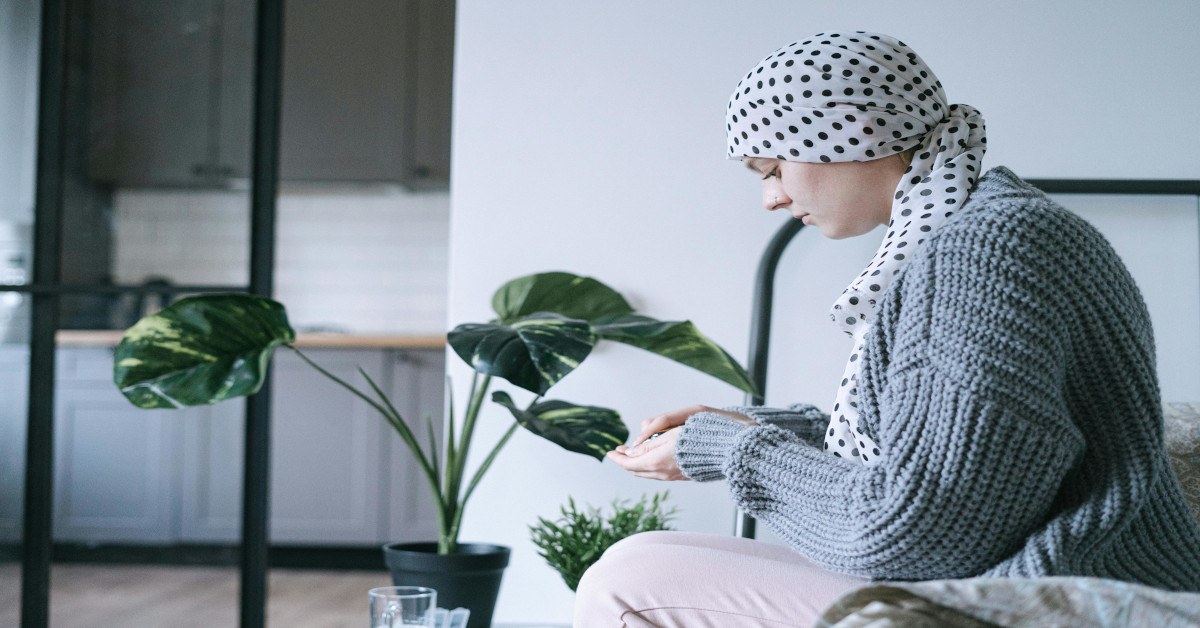 A woman taking medicine while sitting on the bed.