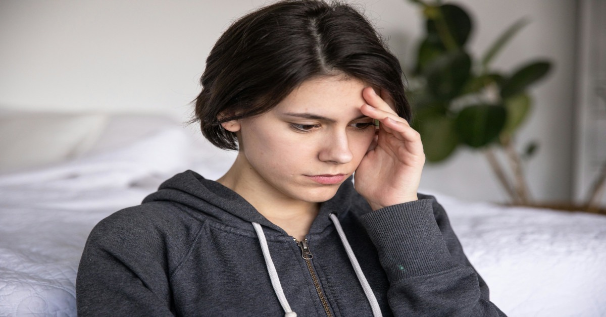 A young woman is touching her head while thinking.