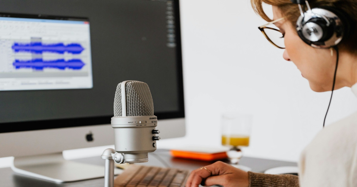 A woman is using a microphone while wearing a headset.