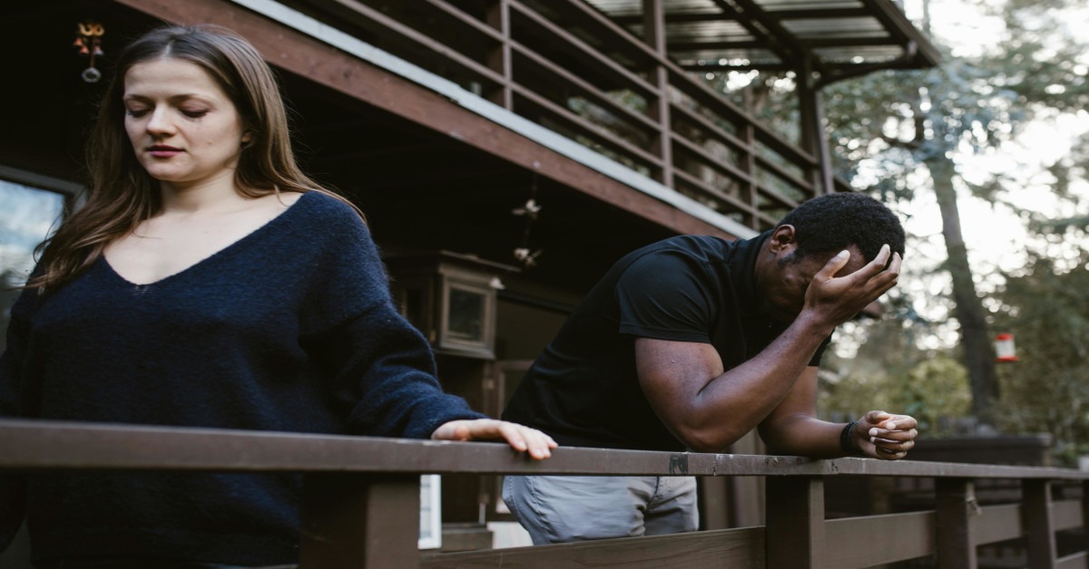 A woman walking away from a man in distress who is holding his head.