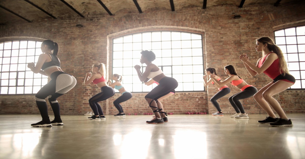 A group of women doing bodyweight squats in the gym.