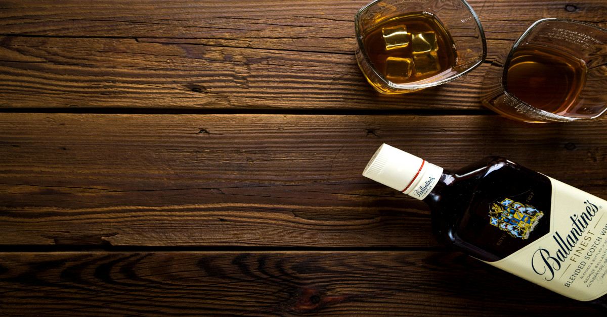 Two glasses of alcohol are sitting on the table, with the bottle is lying next to it.