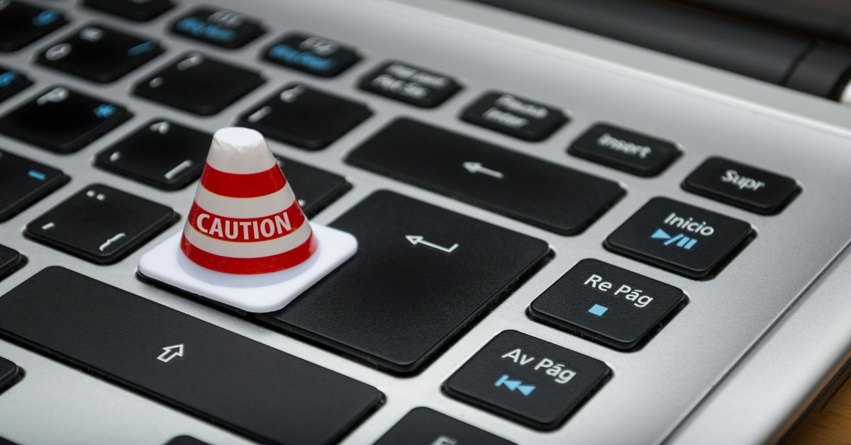 Illustration of a cone reading "warning" standing on a laptop.