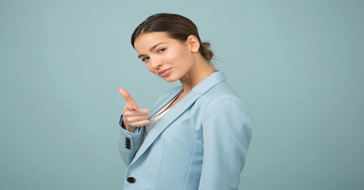 A confident-looking woman pointing toward the camera.