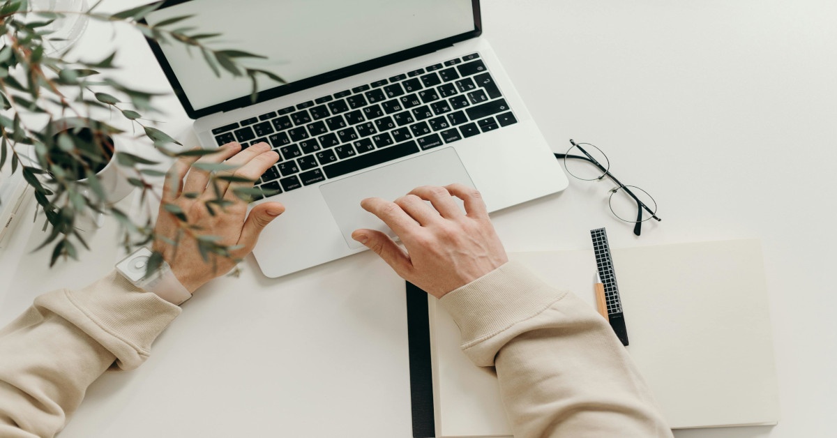 A person typing and working with a laptop.
