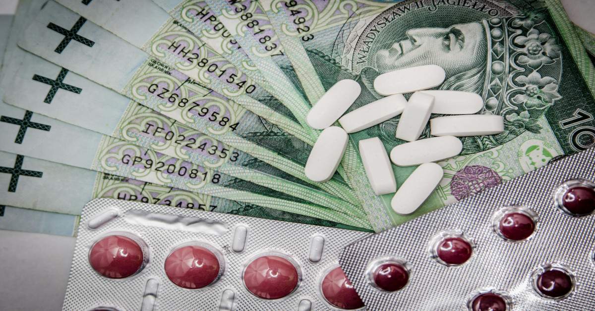 Image of money with pills and tablets lying on top of it, indicating that medication is expensive.