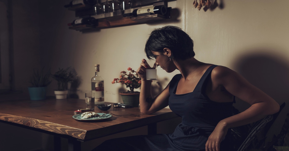 A sad dark skinned woman drinking alcohol.