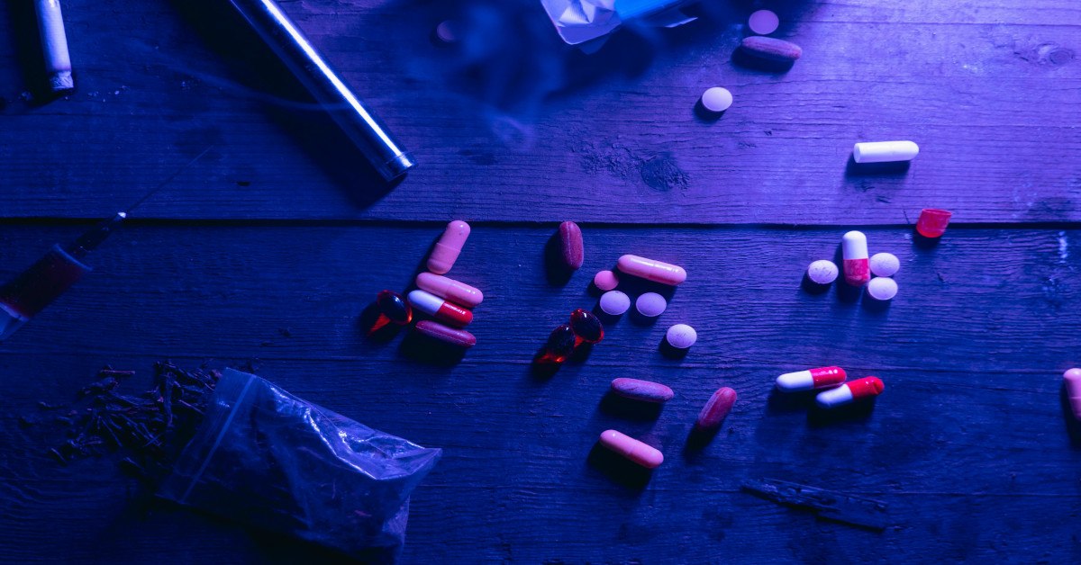 An image showing pills and needles lying on a table, indicating substance abuse.