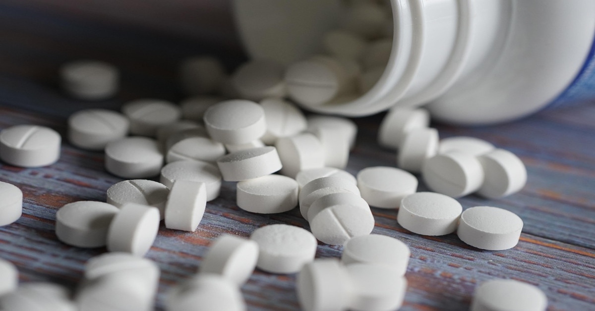 Image of a bottle of medication that's open, with the pills spread over a table.