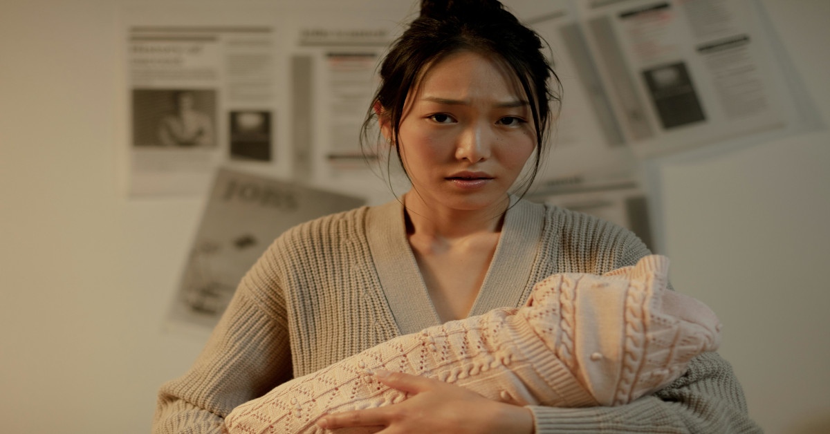 A young woman holding her baby while looking worried.