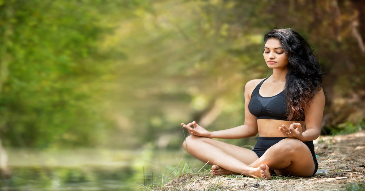 A young woman meditating outside in nature.